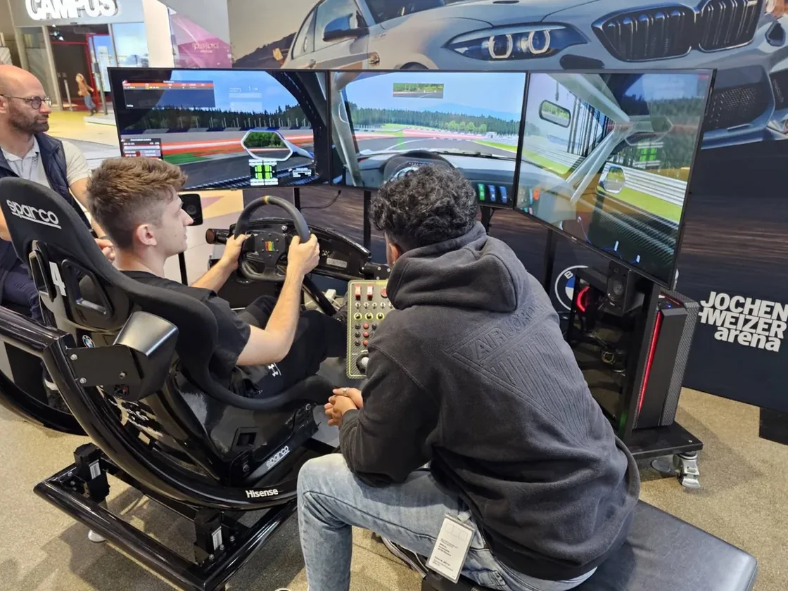 A GitGud coach working with a driver at a triple-screen sim racing rig.