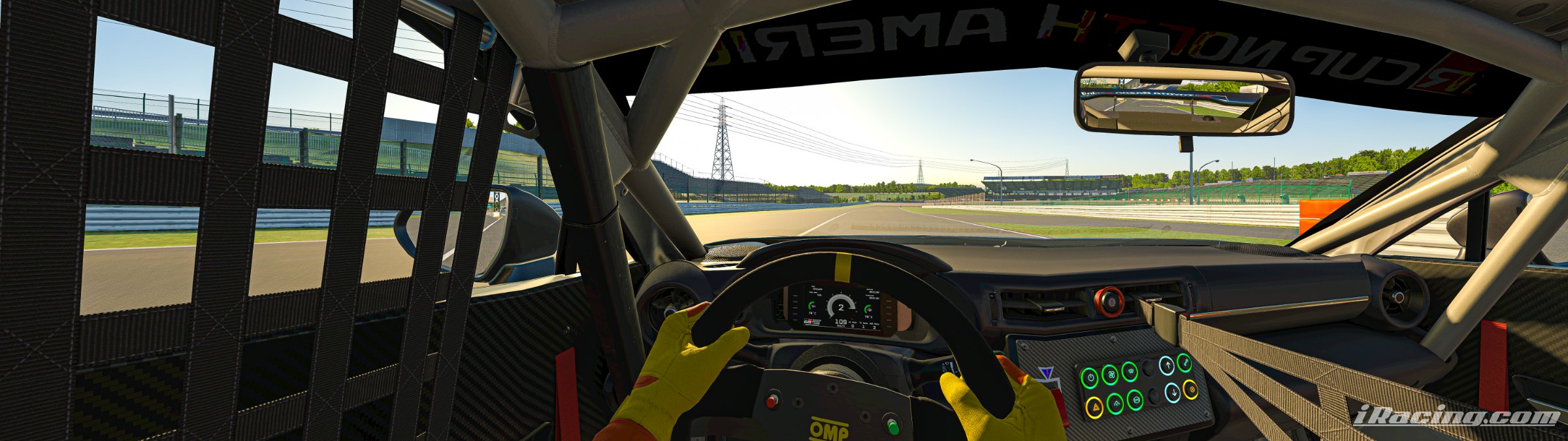 Onboard view from a GT car, hands on the wheel, approaching a straight