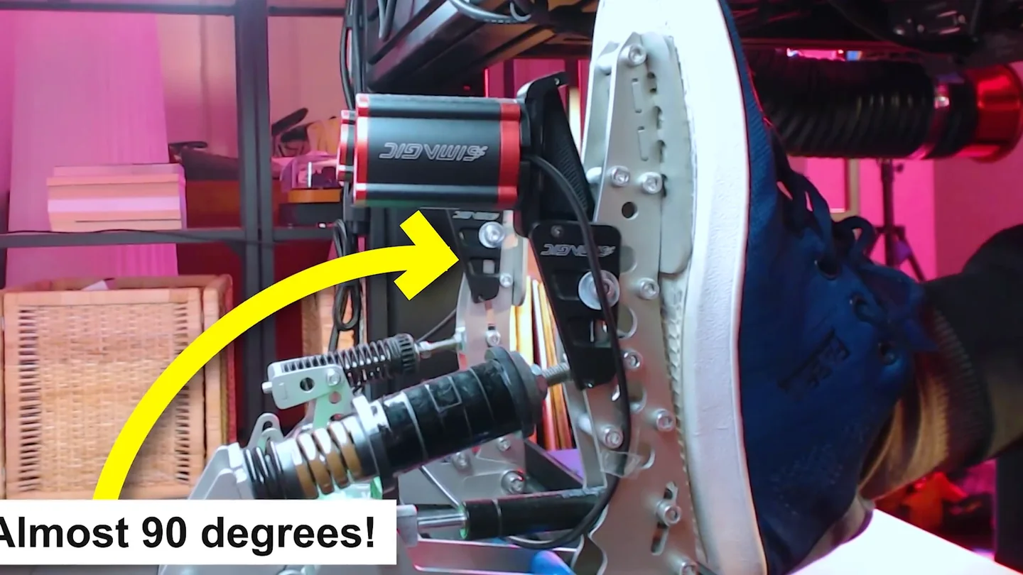 Close-up of a shoe resting on a load cell brake pedal with a yellow arrow and the note almost 90 degrees marking the lower-leg to pedal-face angle that the brake pedal settings sim racing guide recommends.