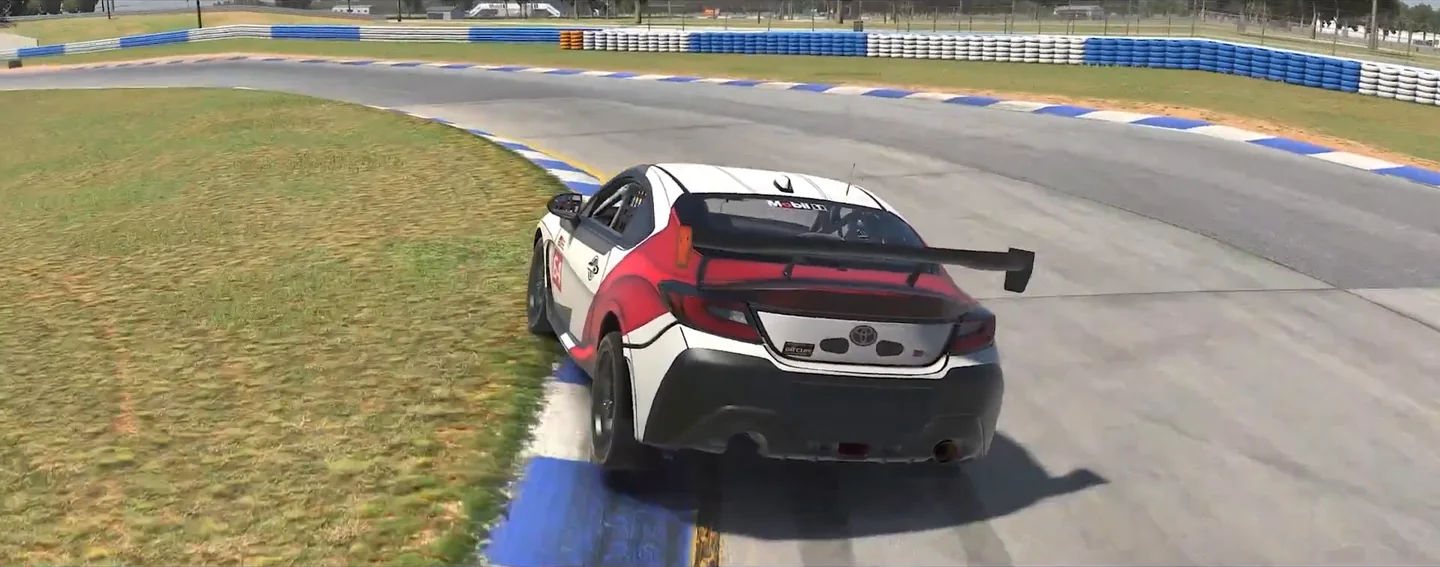 Chase view of a Toyota GR86 in iRacing turned in hard on the apex kerb under trail braking with the rear stepping wide, the moment the video uses to show how slew rate is felt in force feedback settings for sim racing.