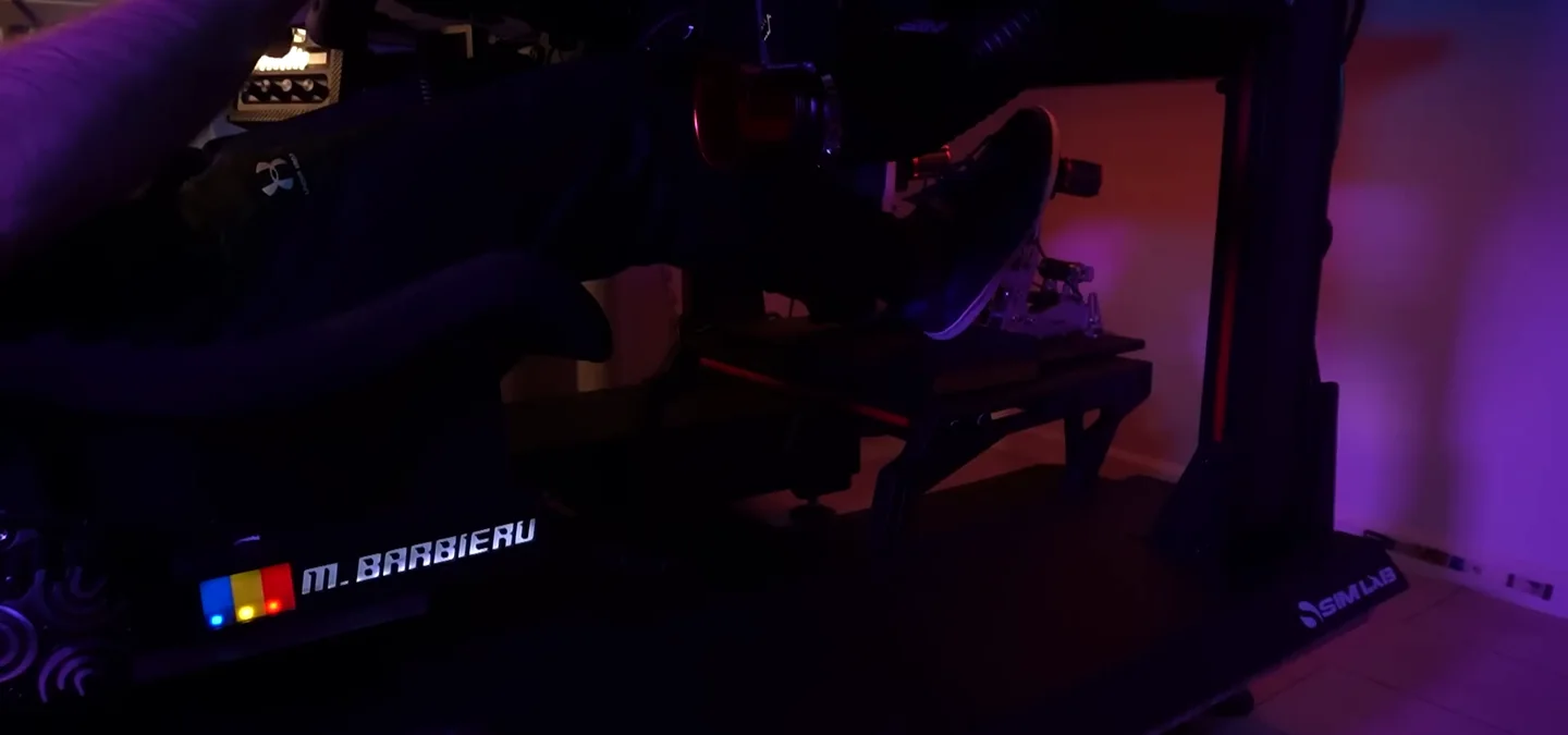The RGB nameplate mounted low on the Sim Lab rig base beside the driver's legs, showing where purely decorative sim racing accessories like this sit.