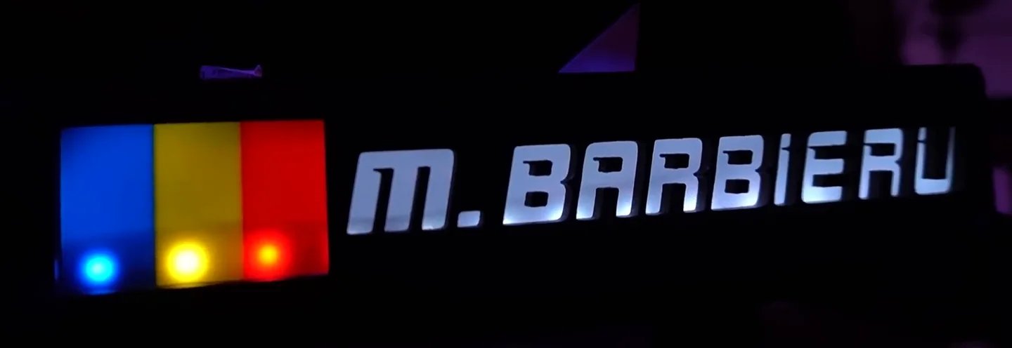 A personalised nameplate lit by RGB LEDs showing a Romanian flag and the name M. Barbieru, the purely decorative entry among these sim racing accessories.