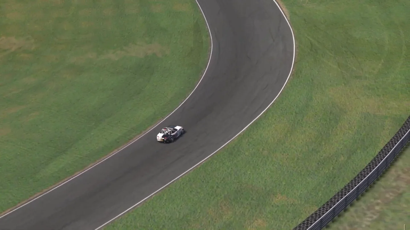 航拍视角下，一台 MX-5 正处于 Lime Rock Park 一个长弯的中段，仍在过弯而不是加速。
