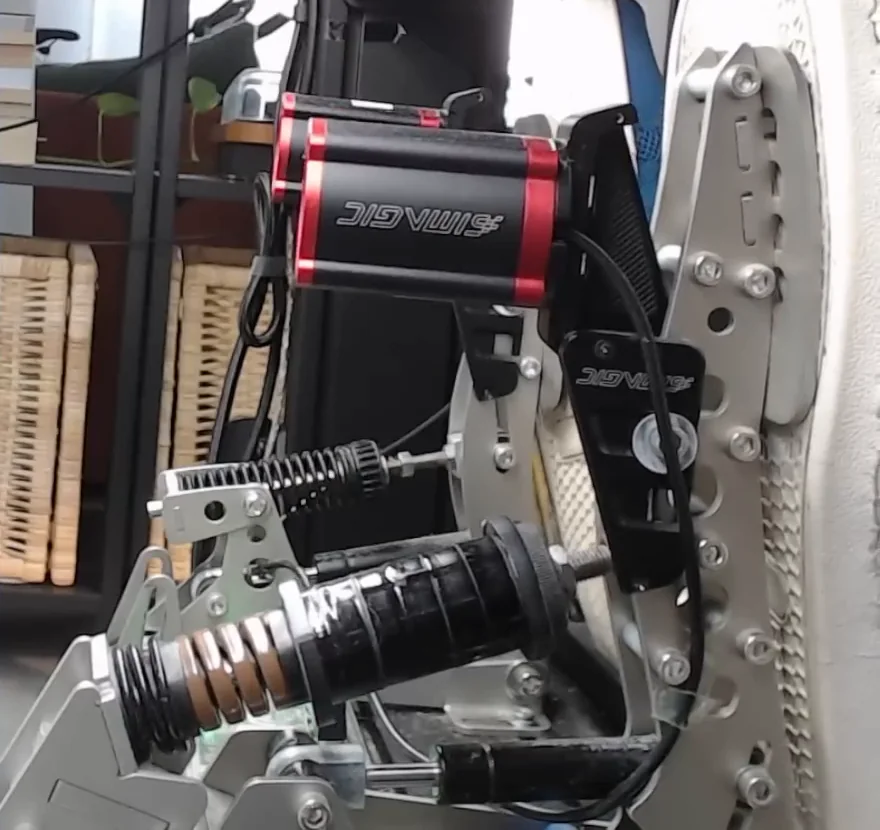 Close-up of the brake pedal's brown and black springs part-compressed at about a third of travel, the two-stage feel these sim racing brake pedal tips explain.