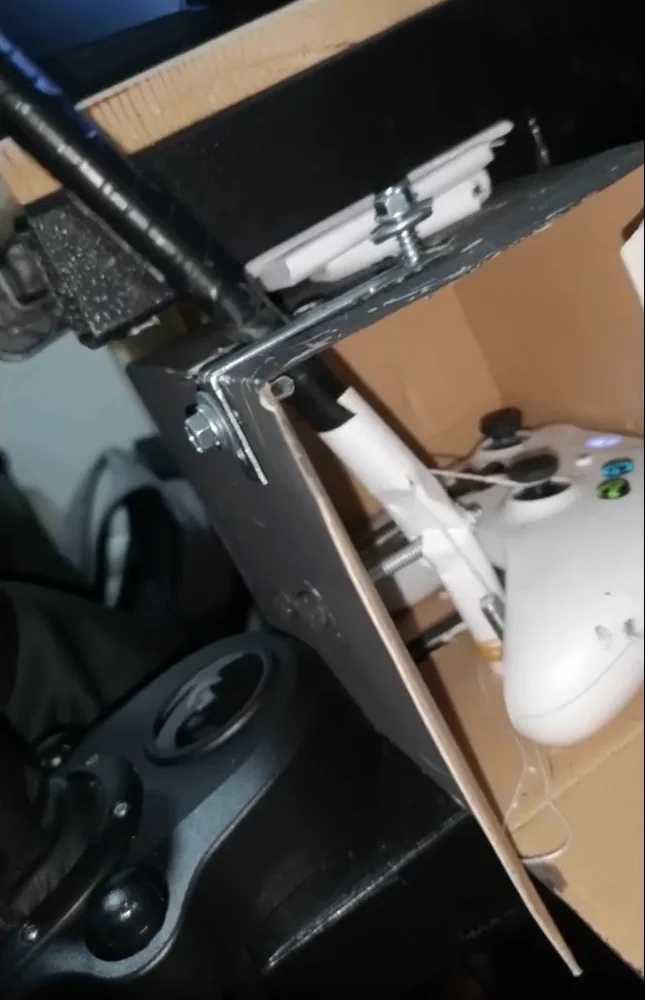 A DIY handbrake built from a cardboard box, a metal rod and a white gamepad whose trigger the rod pulls, the most cost-effective of these cheap sim racing mods.