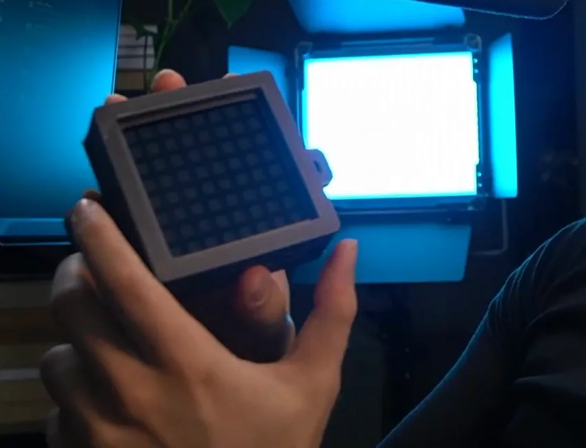 A small unlit LED matrix panel held in the hand beside a studio light, the SimHub-driven flag and gear display among these cheap sim racing upgrades.