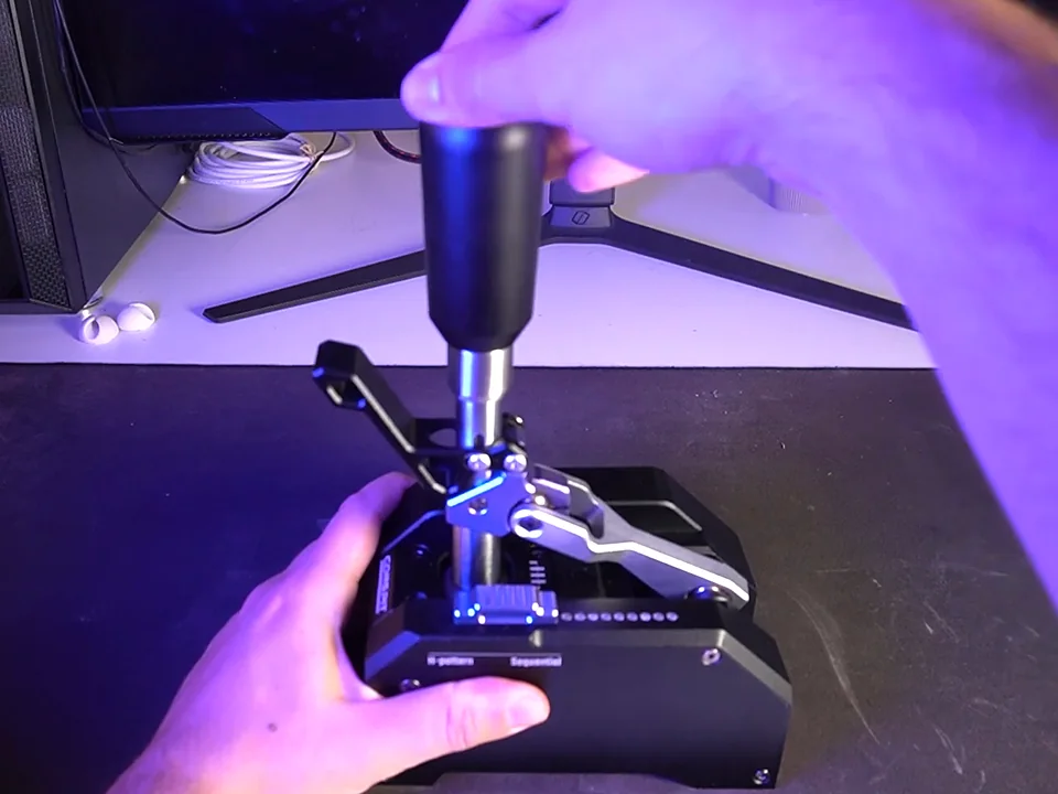 Conspit CHS in sequential mode, one hand on the knob and the other steadying the base, H-pattern and Sequential labels on the front