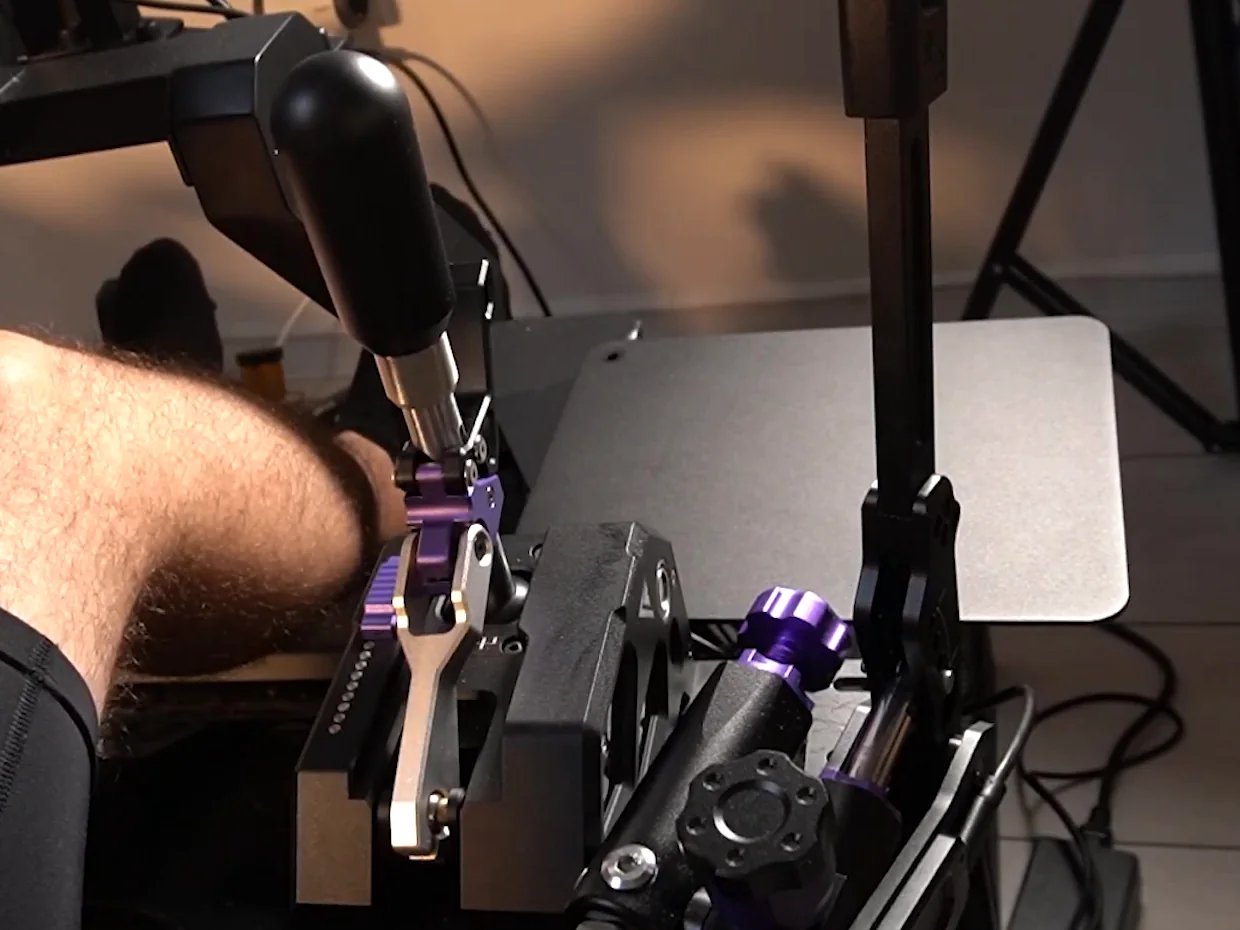 Conspit CHS shifter mounted on a sim rig with a handbrake right beside it and the driver's leg close to the shifter