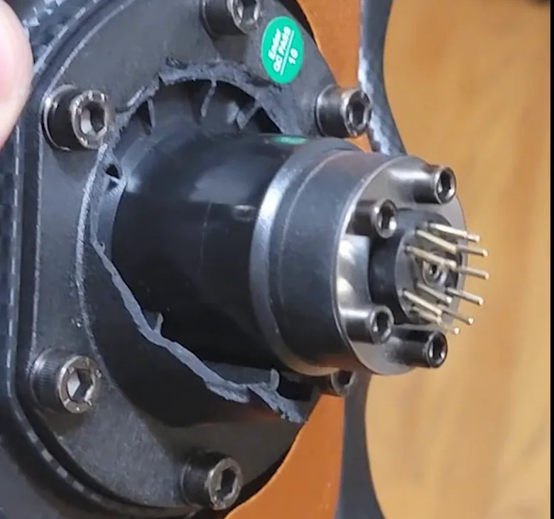 A crack running through the black plastic quick release adapter on a wheel hub, one of the common Fanatec CSL DD problems.