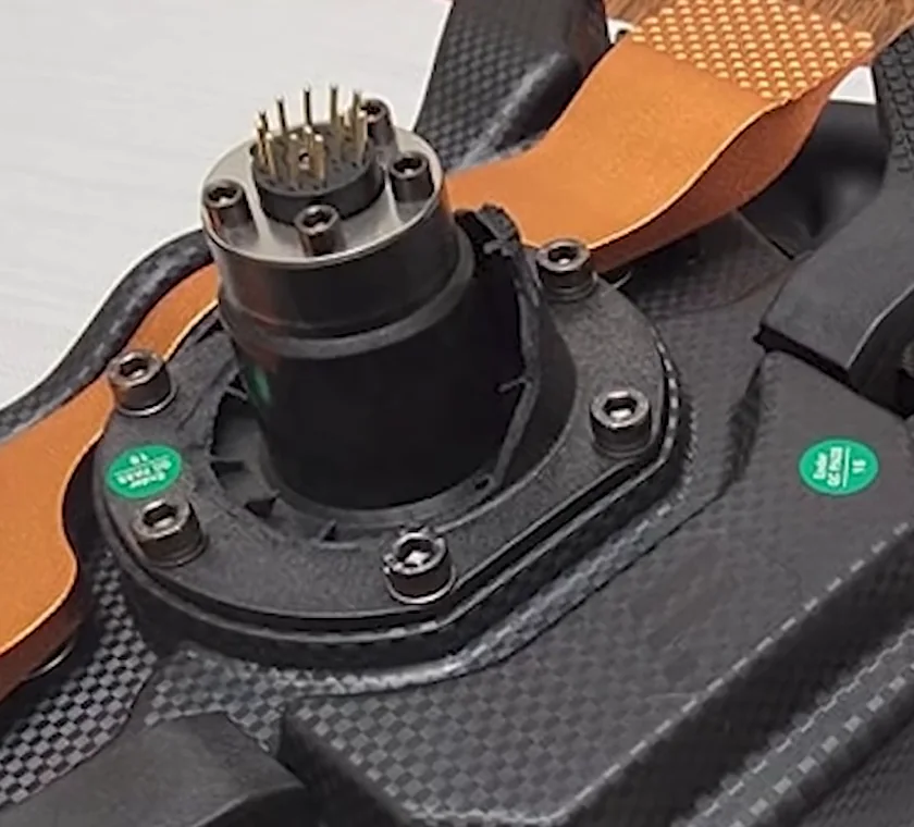 The plastic quick release adapter that ships with the Fanatec CSL DD, bolted to a wheel with its multi-pin connector and hex screws exposed.