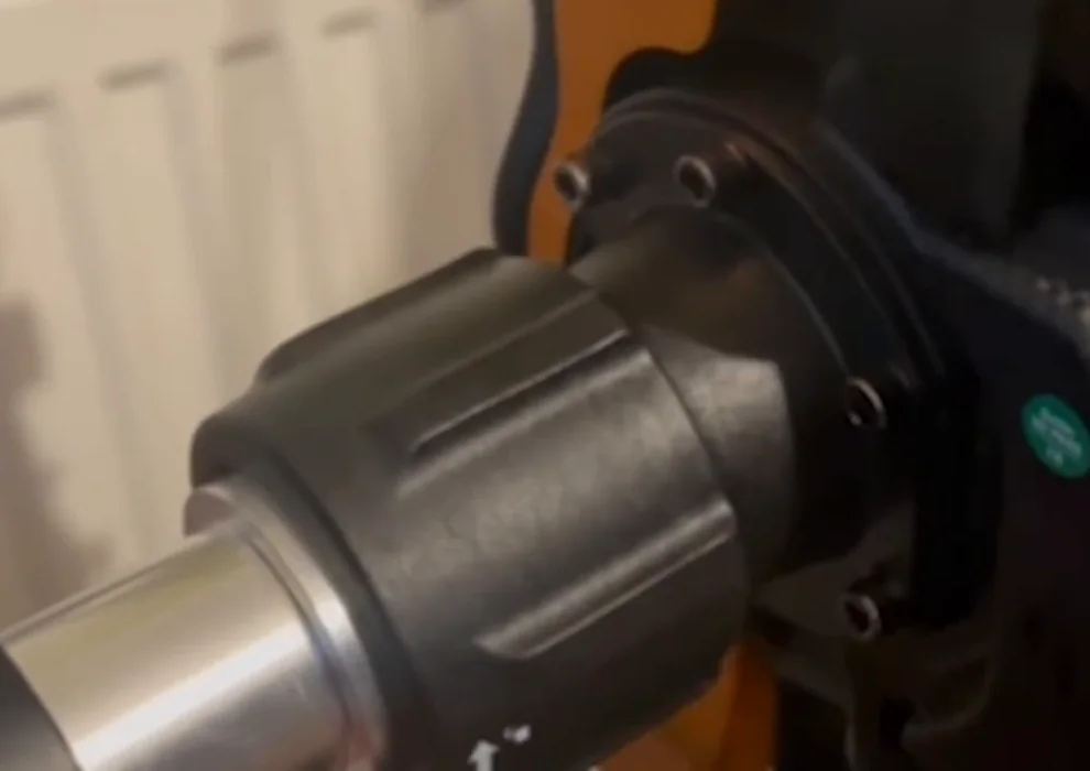 The plastic QR Lite collar clamped over the polished metal shaft of a Fanatec CSL DD, where the two surfaces rub.