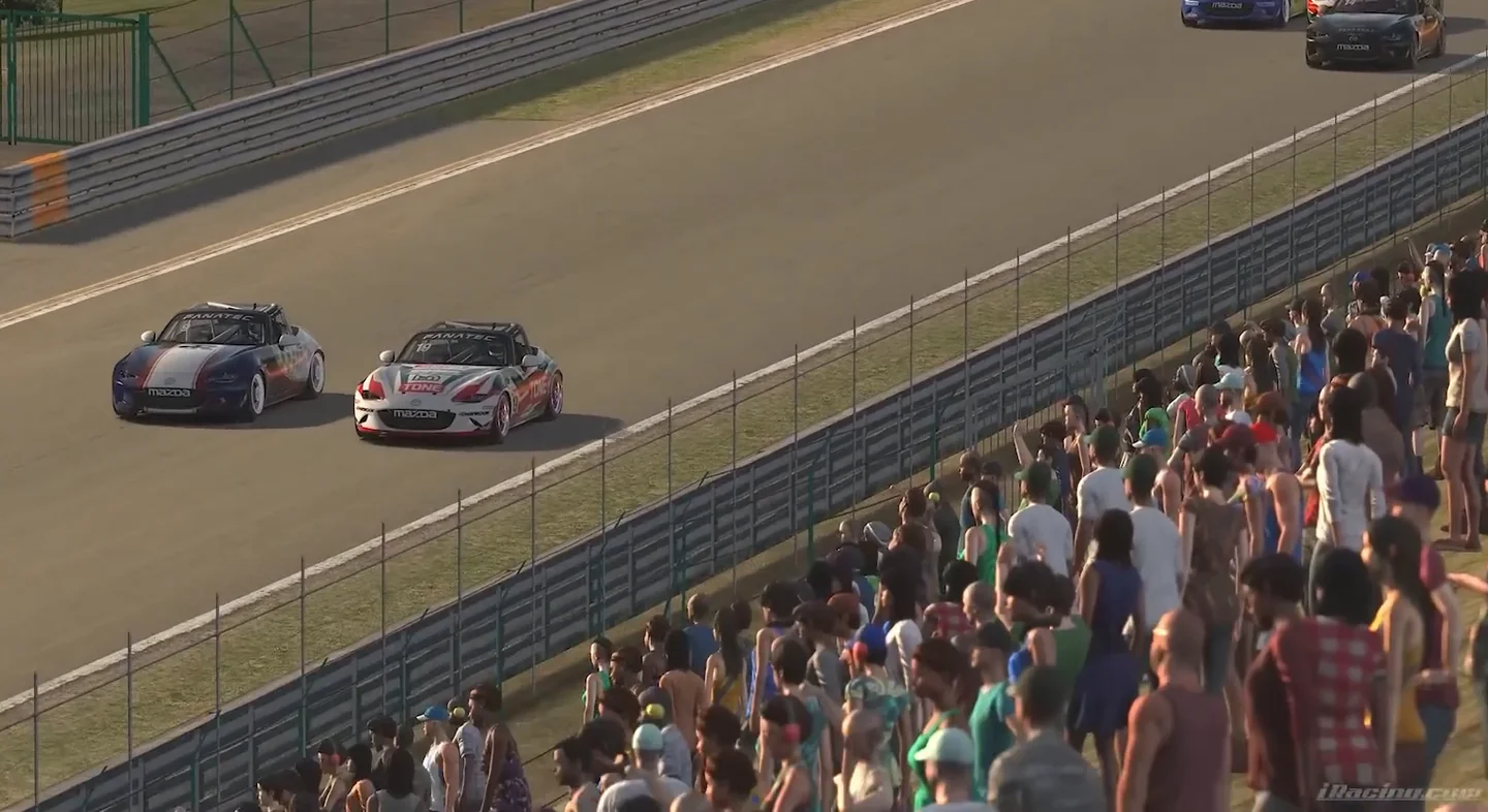Two MX-5 cup cars running side by side past a packed crowd, the close racing a healthy sim racing mindset learns to value.