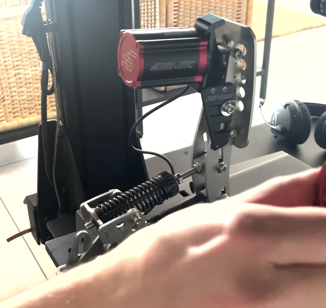 The Simagic reactor bolted beside the Heusinkveld pedal arm through the angled bracket, the completed Simagic haptic reactor Heusinkveld mount before it is checked by hand.